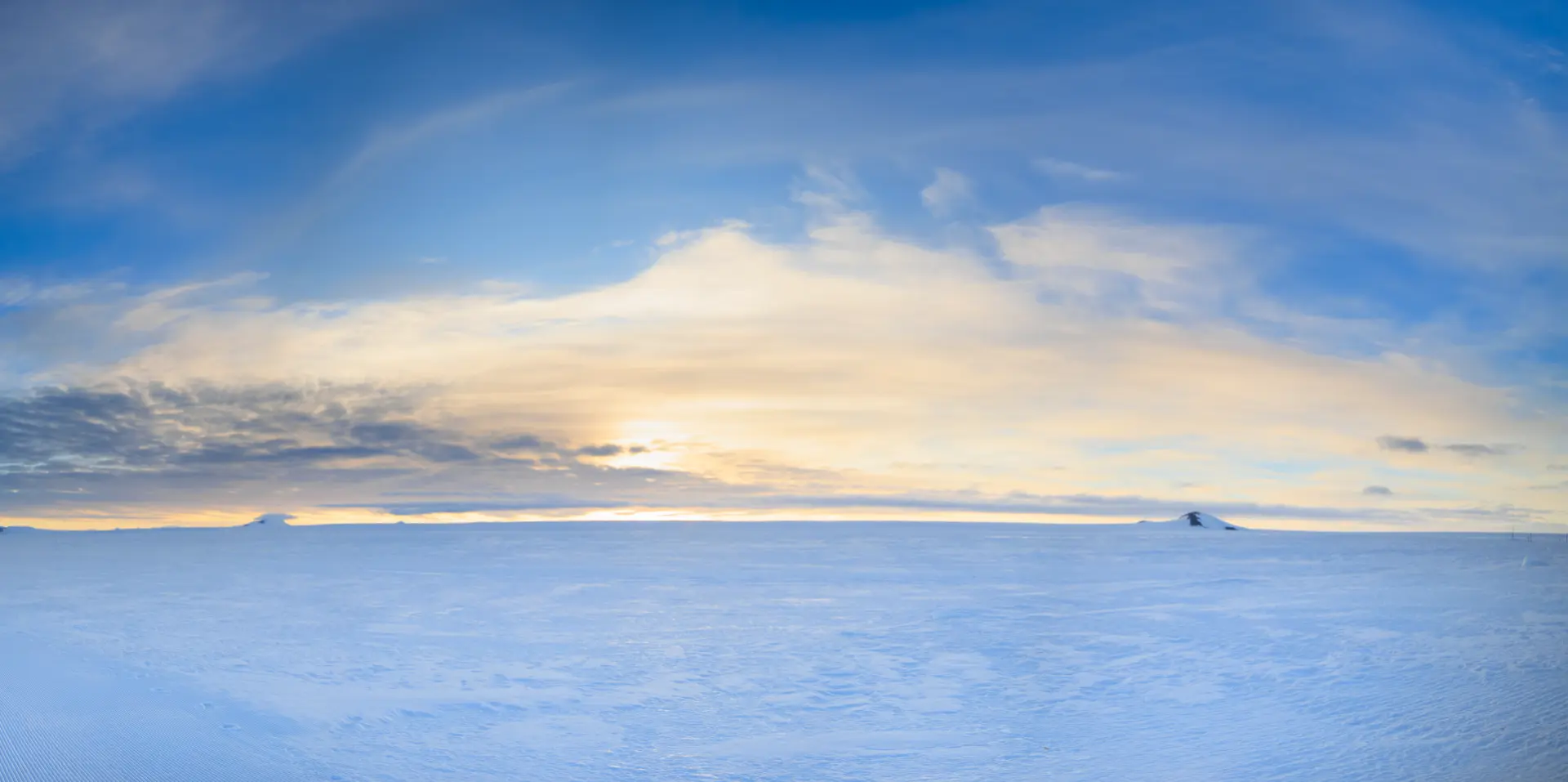 Golden polar light over an endless Antarctic snow plain at sunset