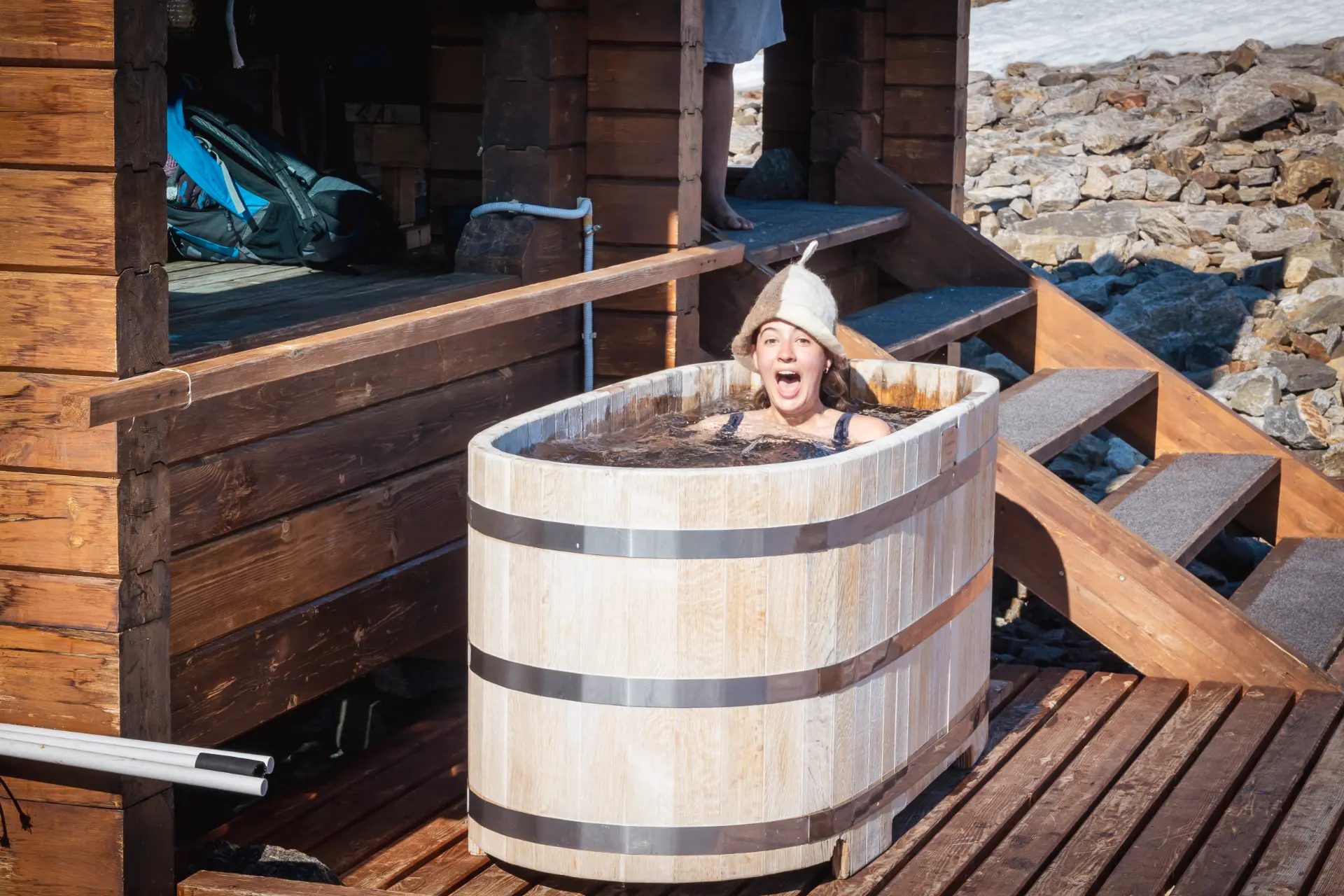 An expedition member reacting during a cold water plunge in a wooden tub outside a cabin
