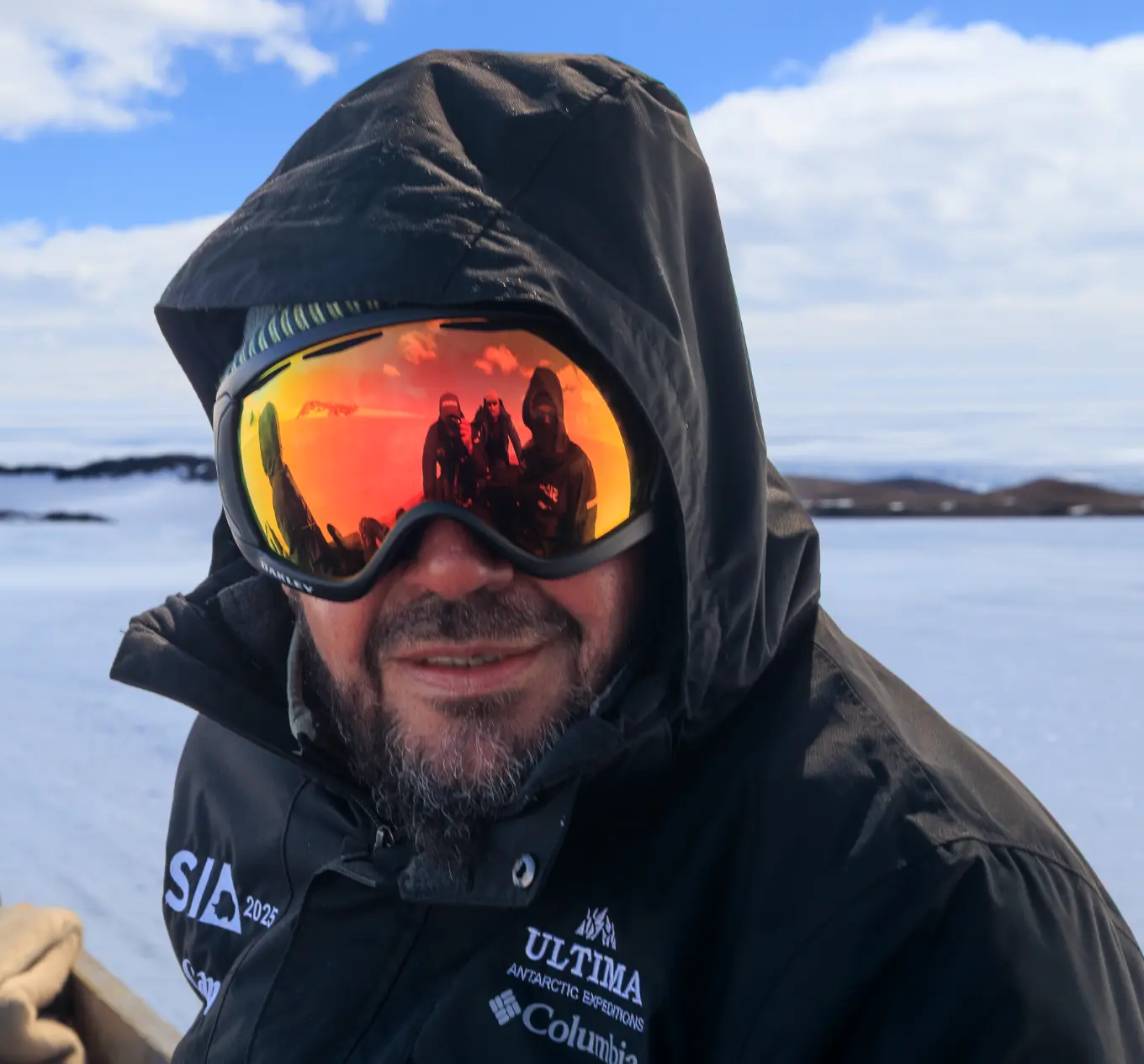 Riaan Manser in Antarctica, hood up and goggles reflecting the expedition team