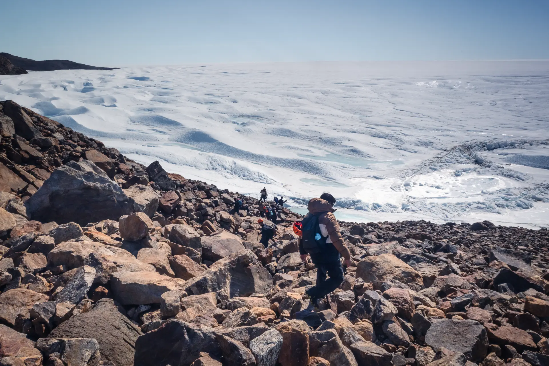 Students descending a rocky Antarctic slope toward the ice field
